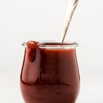 A jar of barbecue sauce with a drip of some down the side.