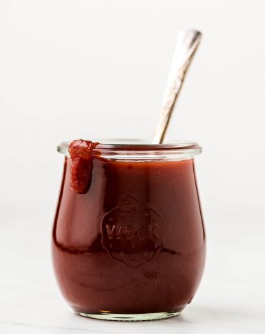 A jar of barbecue sauce with a drip of some down the side.