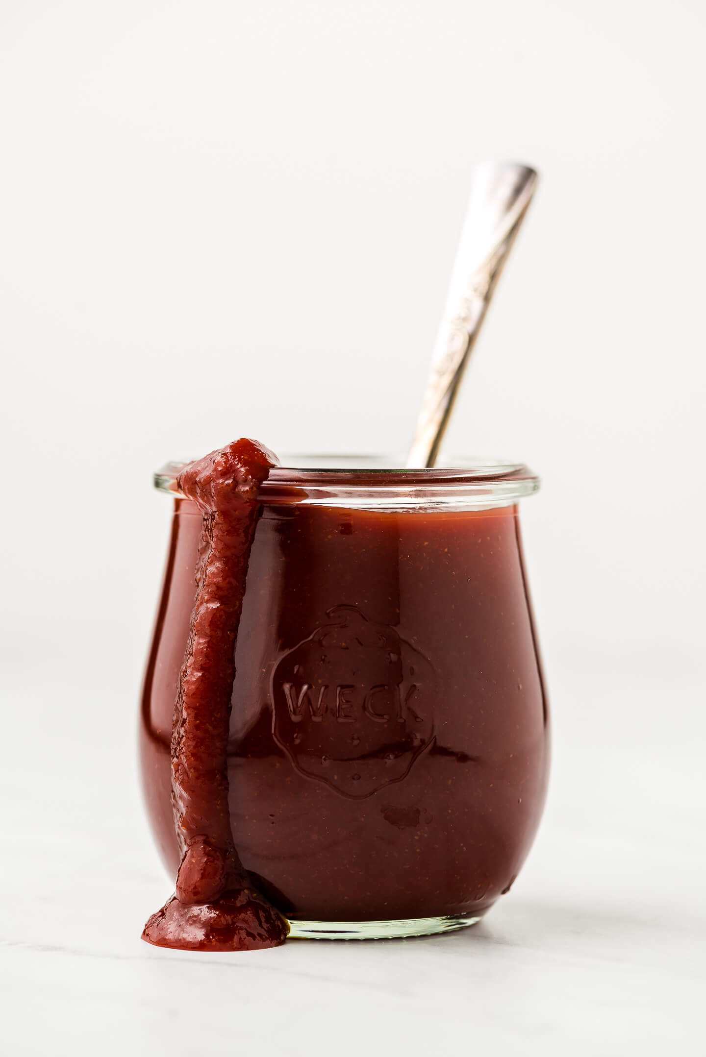 A jar of homemade barbecue sauce with some dripping down the side of the jar.