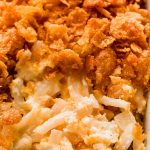 Close up shot of creamy cheesy potato casserole with cornflakes on top.