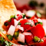 Close up shot of a chip with Pico de Gallo on it.