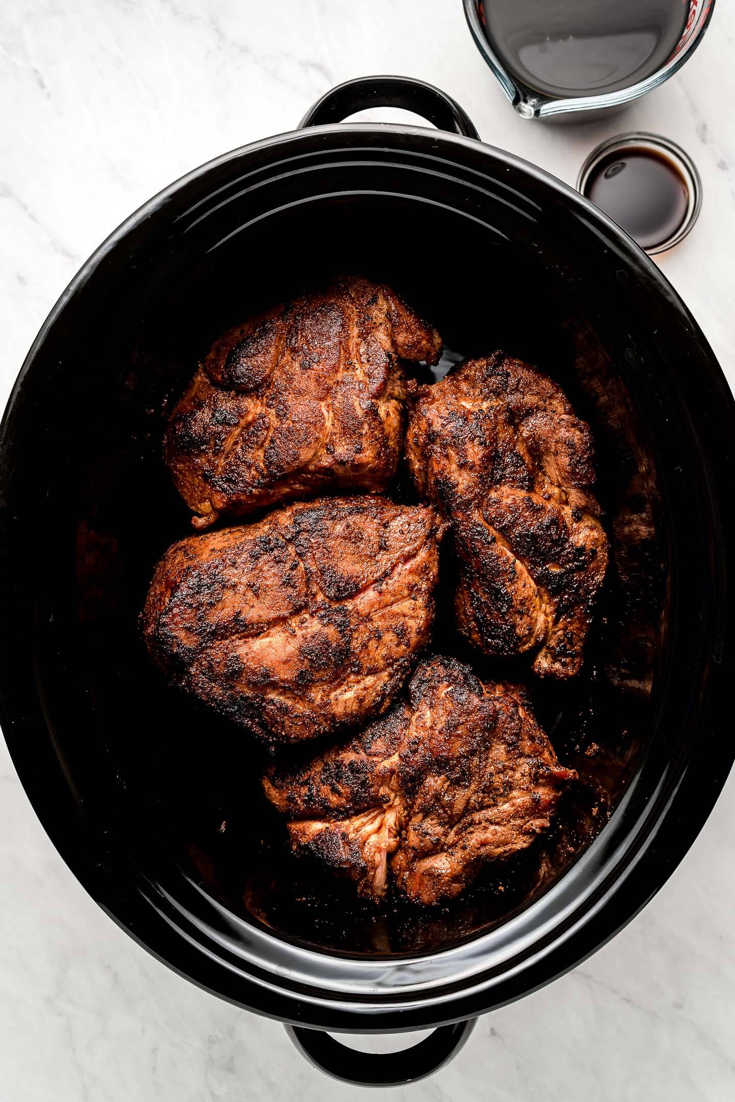 A slow cooker with browned pork roast.