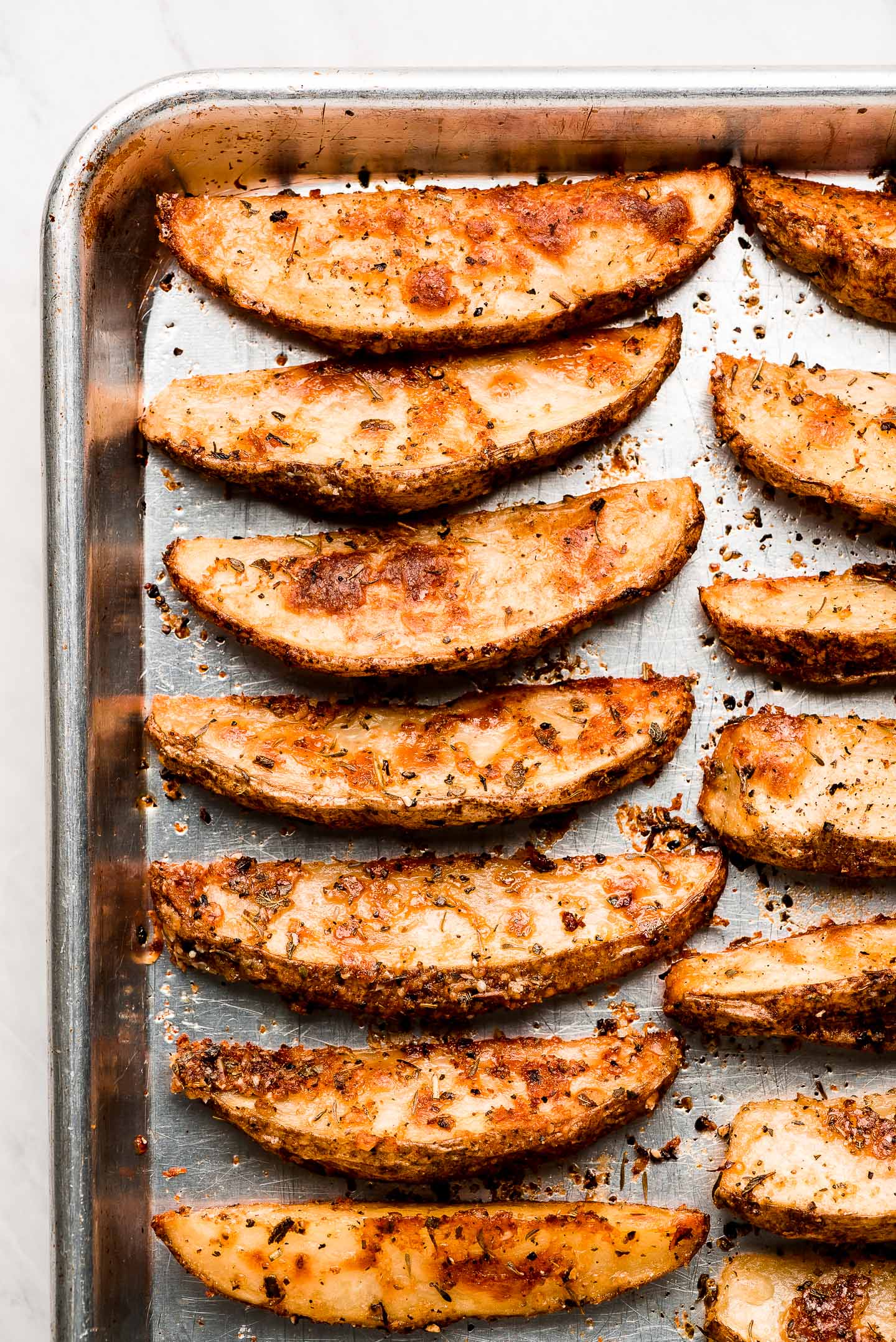 Crispy Baked Potato Wedges uniformity lined up on a baking sheet.