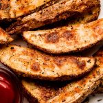 Close up of crispy Baked Potato Wedges on a plate with ketchup.
