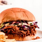 Shredded bbq chicken on a sandwich with coleslaw.