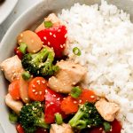 A bowl of rice and chicken stir fry with vegetables.