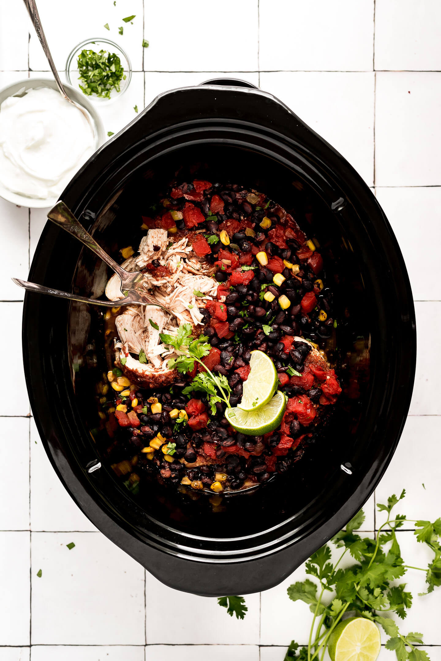 Shredding chicken in a slow cooker with tomatoes, black beans, and corn.