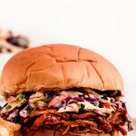 Shredded bbq chicken on a sandwich with coleslaw.