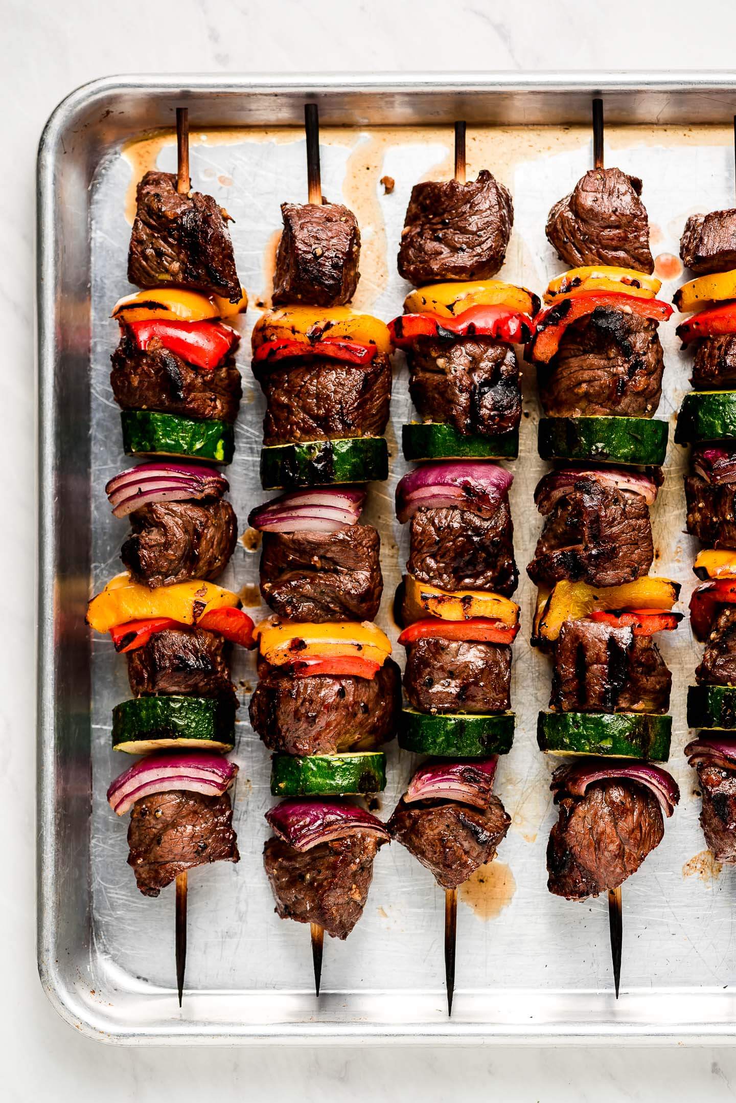 Beef and vegetable kabobs on a rimmed baking sheet.