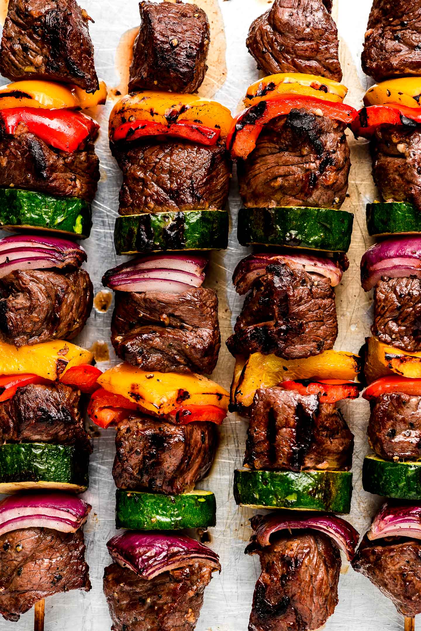 Four kabobs with steak, bell peppers, red onion, and zucchini.