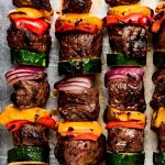 Four kabobs with steak, bell peppers, red onion, and zucchini.