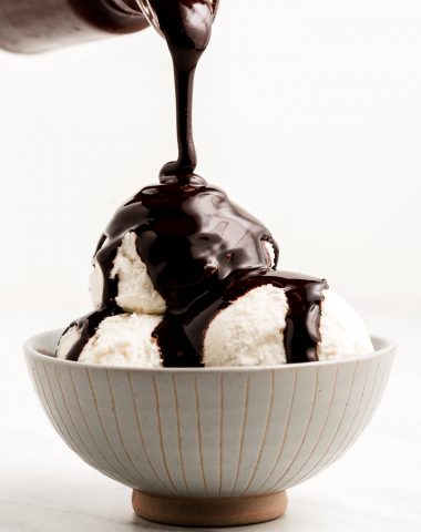 Pouring Chocolate Sauce over scoops of ice cream in a bowl.