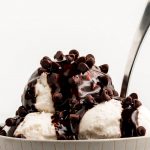 A bowl of ice cream topped with chocolate sauce and chocolate chips.