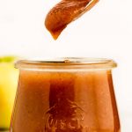 Lifting a spoon of apple butter out of a jar.
