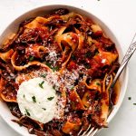 Beef Ragu in a bowl topped with ricotta and parmesan.