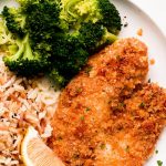 Close up of a breaded tilapia fillet on a plate.