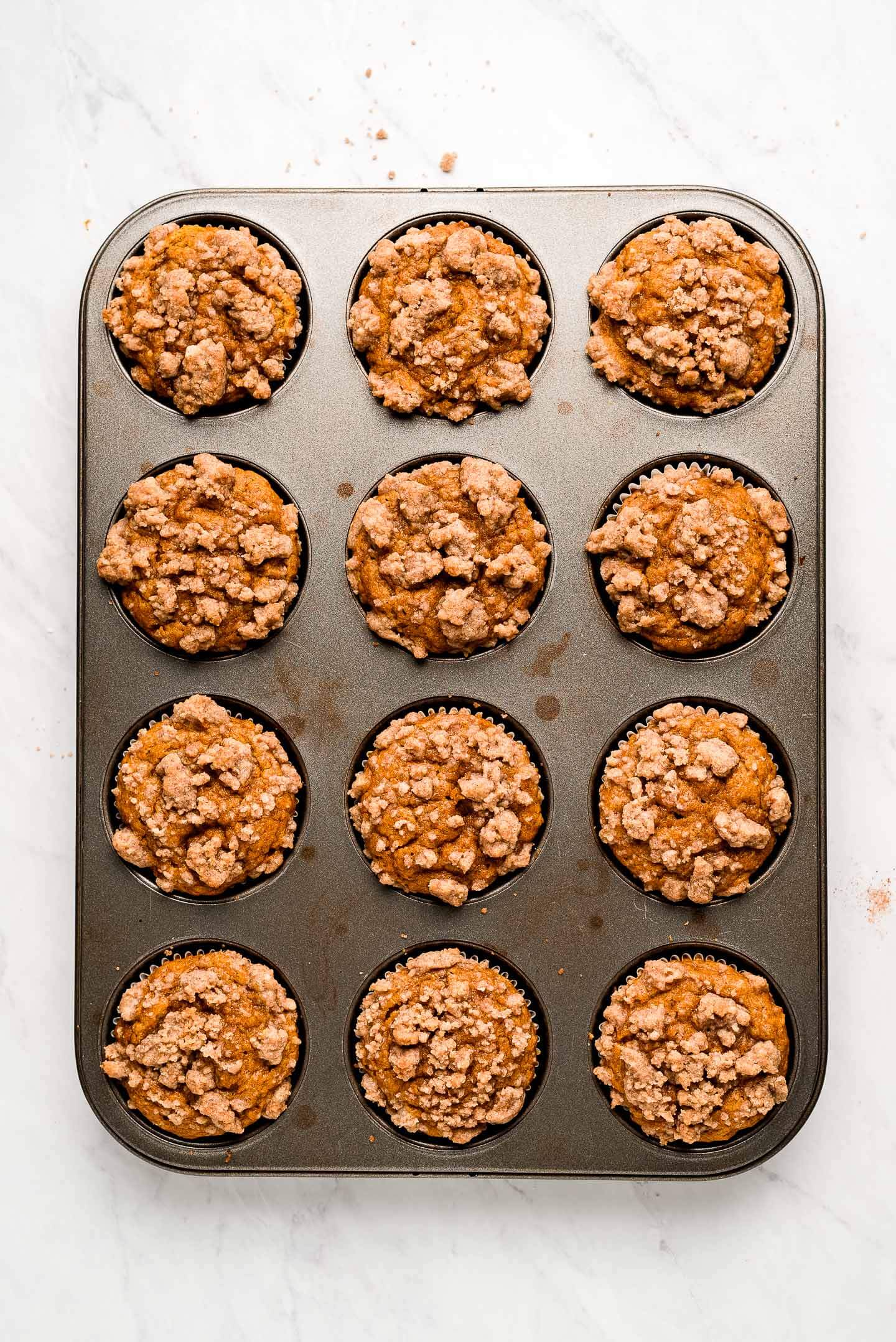 A muffin tin with baked pumpkin streusel muffins.