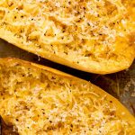 Two halves of spaghetti squash topped with parmesan cheese and pepper.