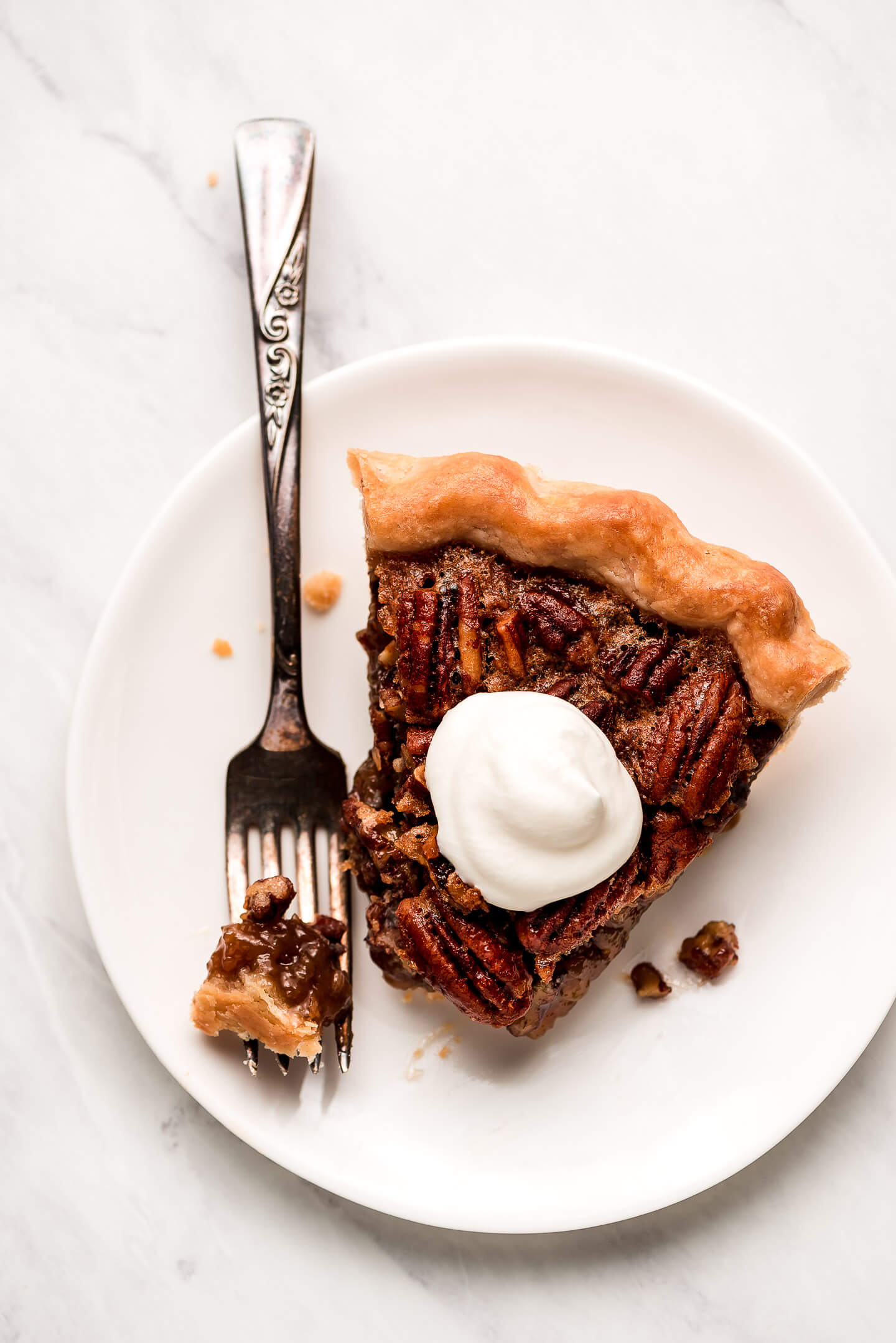A slice of pecan pie garnished with a dollop of whipped cream.
