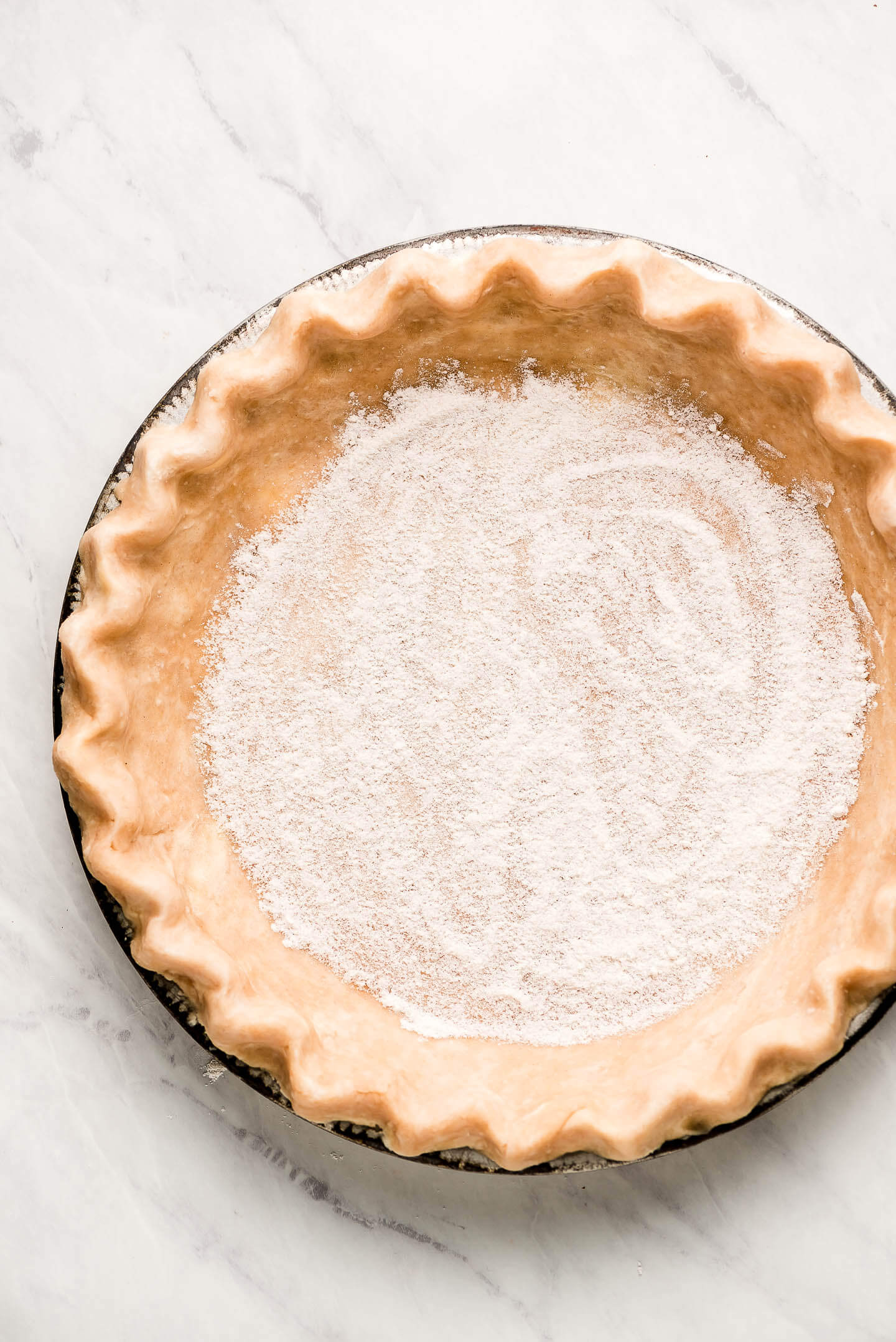 Uncooked pie shell with fluted edges and sugar/flour sprinkled on the bottom.
