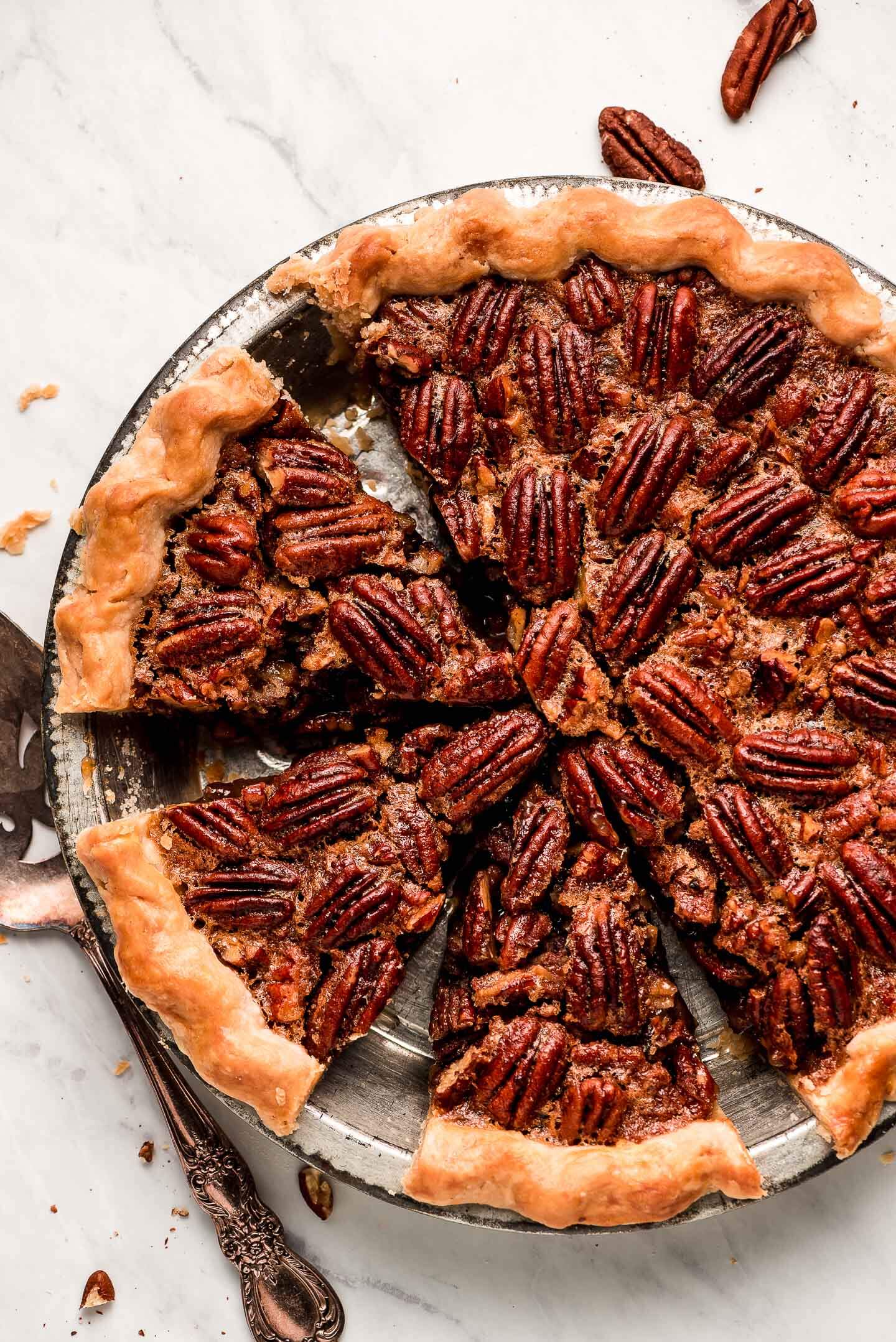 Pecan Pie in a metal tin with half of it cut in slices.