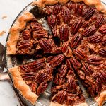 Pecan Pie in a metal tin with half of it cut in slices.
