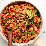 Chicken Pad Thai in a skillet with a wooden spoon in the side.