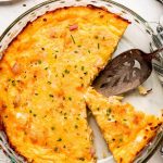 A Ham and Cheese Hash Brown Quiche with slices cut out and on multiple plates.